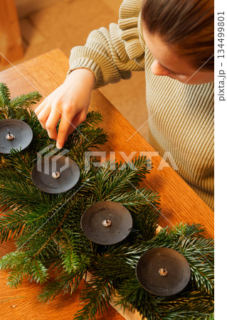 Hands of girl arranging pine branches for advent wreath Hands of girl arranging pine branches for advent wreath 134499801