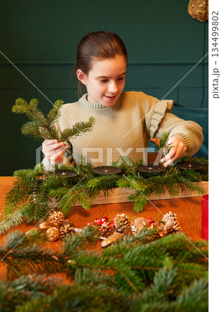 Girl preparing Advent wreath with fir branches at home 134499802