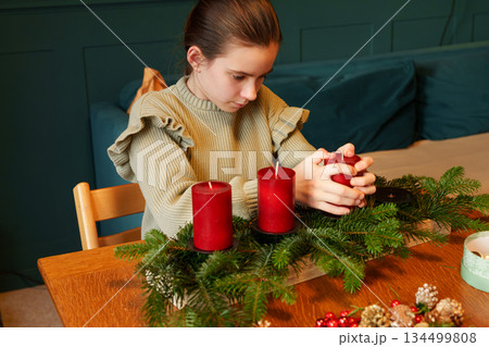 Girl with Advent wreath and candles sitting at festive table 134499808
