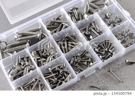 Set of assorted screws organized in plastic storage box on gray background. Hardware tools concept. Set of assorted screws organized in plastic storage box on gray background. Hardware tools concept. 134500794