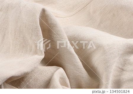 Draped natural beige linen fabric texture with folds 134501824