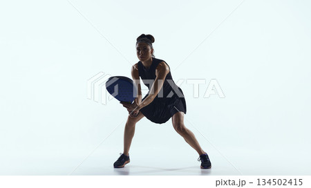 Female padel player prepares to receive the ball in minimalist studio space Female padel player prepares to receive the ball in minimalist studio space 134502415