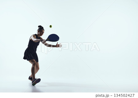 Female padel player controlled backhand shot on white background. Female padel player controlled backhand shot on white background. 134502427
