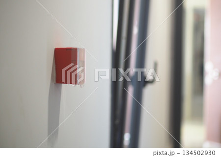 Fire alarm on wall in indoor hallway setting Fire alarm on wall in indoor hallway setting 134502930