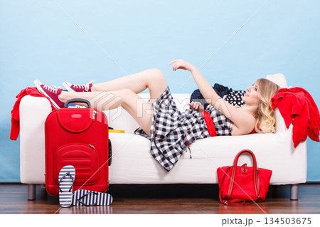 Woman relaxing after packing suitcase for vacation Woman relaxing after packing suitcase for vacation 134503675