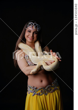 Woman performs dance with snake during a cultural event in a dark setting Woman performs dance with snake during a cultural event in a dark setting 134503840