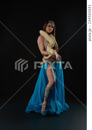 Woman performs dance with snake in studio setting during evening hours 134503841