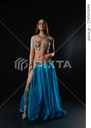 Woman dances with a snake in a dark setting at a cultural event 134503844