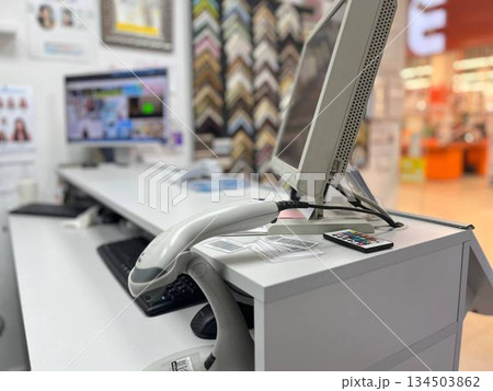 A desk with a computer monitor, keyboard, and barcode scanner against shelves with pictures, perfect for home office setups, inventory management themes, and organized workspace photography. A desk with a computer monitor, keyboard, and barcode scanner against shelves with pictures, perfect for home office setups, inventory management themes, and organized workspace photography. 134503862