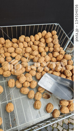 Whole walnuts in shell scattered in a metal basket with a scoop at a local market. The image represents natural food, harvest, and healthy nutrition concept 134504056