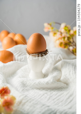 Easter spring background. Egg in a ceramic egg holder stand with flowers. Minimalistic Easter spring background. Egg in a ceramic egg holder stand with flowers. Minimalistic 134504279