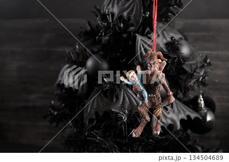 Dark Christmas Ornament. A creepy Krampus ornament hangs on a black Christmas tree Dark Christmas Ornament. A creepy Krampus ornament hangs on a black Christmas tree 134504689