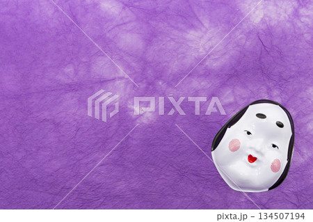 紫色の和紙背景に配置されたおかめ（お多福）のお面 節分・招福素材 134507194