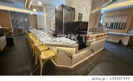 A sleek dessert shop with marble counters, yellow chairs, and a wall of toppings offers a clean, customizable experience A sleek dessert shop with marble counters, yellow chairs, and a wall of toppings offers a clean, customizable experience 134507349
