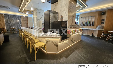 A sleek dessert shop with marble counters, yellow chairs, and a wall of toppings offers a clean, customizable experience 134507351