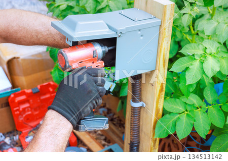 Worker operates power drill during installation at home garden 134513142