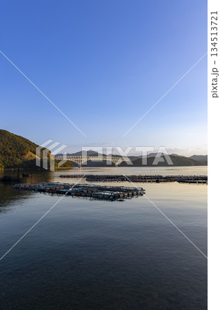 朝日に照らされる長崎県新上五島町の若松大橋と養殖いかだ 134513721