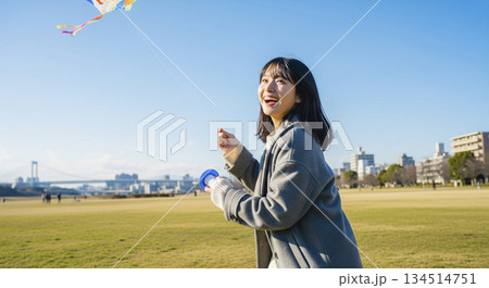 河川敷で凧揚げをする女性 134514751