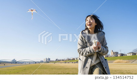 河川敷で凧揚げをする女性 134514752
