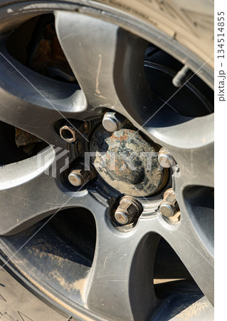 Close up of a dirty car wheel with lug nuts and disc brake 134514855