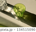 光が当たり影が落ちているペットボトルとグリーンのコップ 134515090