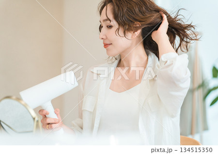 ヘアドライヤーでヘアブロー・髪の毛を乾かす女性（ヘアケア） 134515350