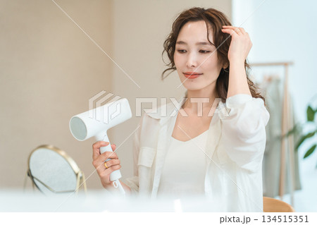 ヘアドライヤーでヘアブロー・髪の毛を乾かす女性（ヘアケア） 134515351