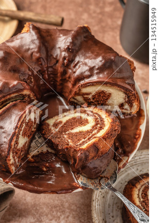 Chocolate marble bundt cake or zebra cake with chocolate glaze sliced on brown table background, close up Chocolate marble bundt cake or zebra cake with chocolate glaze sliced on brown table background, close up 134515949