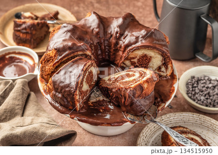 Chocolate marble bundt cake or zebra cake with chocolate glaze sliced on brown table background 134515950