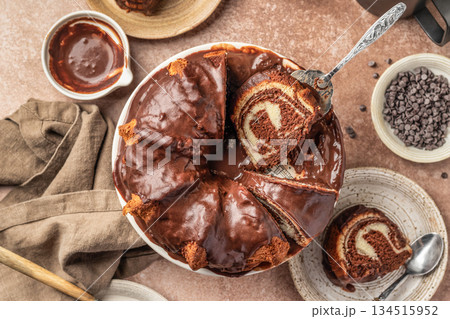 Chocolate marble bundt cake or zebra cake with chocolate glaze sliced on brown table background top view 134515952