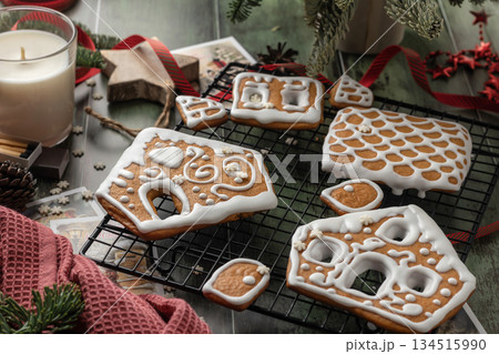 Homemade gingerbread house. Pieces for building a gingerbread house decorated with sugar icing on festive wooden table. Christmas Holiday tradition Homemade gingerbread house. Pieces for building a gingerbread house decorated with sugar icing on festive wooden table. Christmas Holiday tradition 134515990