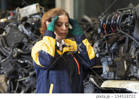 Technician female worker feeling tired and frustration from working in garage scrap yard car workshop warehouse. 134518722
