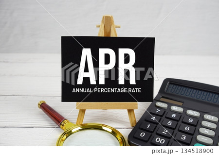 APR Annual Percentage Rate text with magnifying glass and calculator on wooden background 134518900