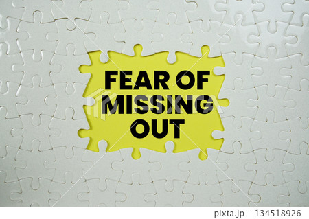 Jigsaw puzzle with a missing piece with "Fear of missing out" on yellow background 134518926