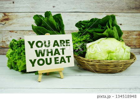 "You are What You Eat" message on a small easel next to a basket of fresh green leafy vegetables 134518948