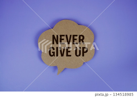 Never Give Up text with speech bubble top view on purple background 134518985