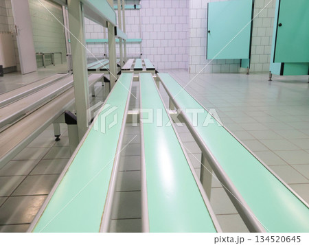 Bench in empty locker room at sports club. Room with lockers for visitors. Fitness center and swimming pool. Sports and health. Bench in empty locker room at sports club. Room with lockers for visitors. Fitness center and swimming pool. Sports and health. 134520645