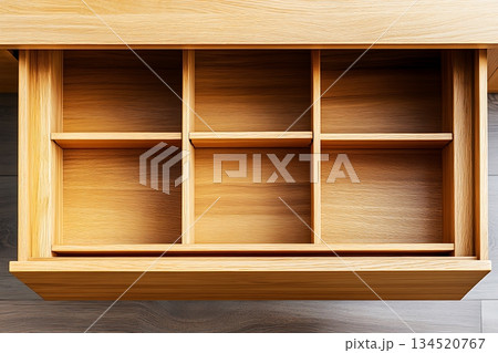 An open wooden drawer exhibits six compartments over the laminated grey floor 134520767
