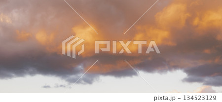 dramatic sunset sky panorama: contrast of dark storm clouds and bright orange glow at twilight 134523129
