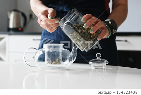 Girl Pouring Green Tea Into Teapot In The Kitchen 134523438