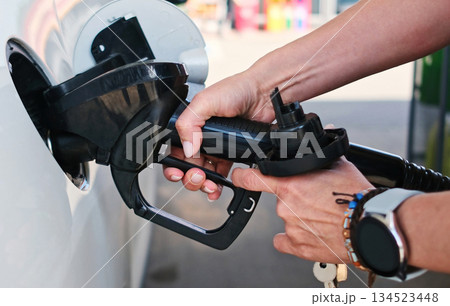 Girl Inserts A Fuel Nozzle Into A Car Gas Tank On A Petrol Station Girl Inserts A Fuel Nozzle Into A Car Gas Tank On A Petrol Station 134523448