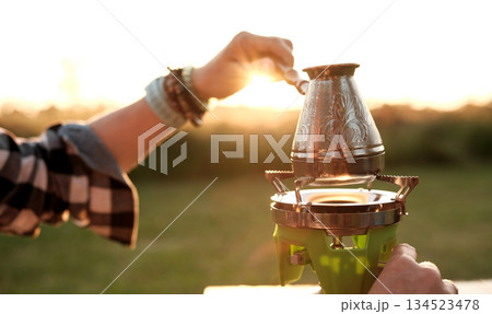 Woman Making Coffee In A Cezve On A Portable Camping Stove Woman Making Coffee In A Cezve On A Portable Camping Stove 134523478