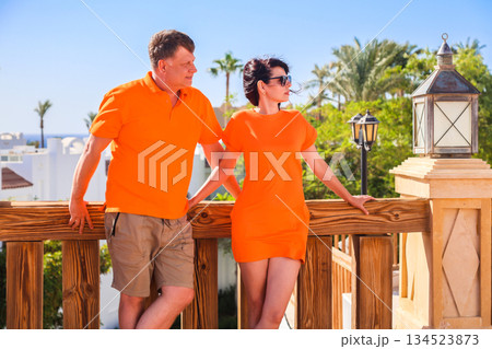 Adult lovers in bright orange clothes on holiday together at a resort Adult lovers in bright orange clothes on holiday together at a resort 134523873
