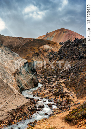 Rugged rhyolite volcanic mountain and stream in Landmannalaugar, Icelandic Highlands Rugged rhyolite volcanic mountain and stream in Landmannalaugar, Icelandic Highlands 134525420