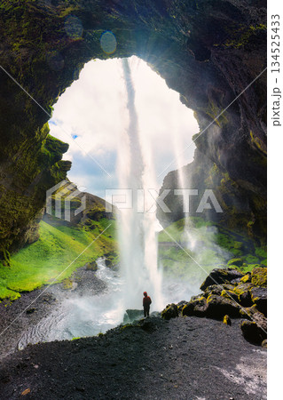 Powerful waterfall Kvernufoss flowing from cliff with tourist standing in summer at Iceland 134525433