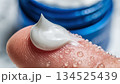 瑞々しい水滴がついた指先に優しくのせられた白い保湿クリームのクローズアップ 134525439