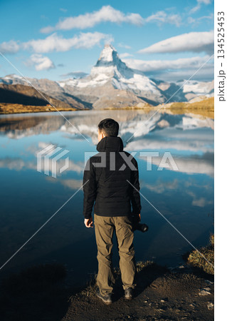 Man standing with camera at Lake Stellisee with Matterhorn mountain in Switzerland 134525453