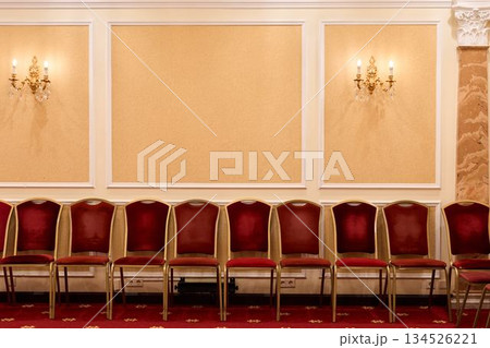 Stylish Arrangement Of Crimson Seats Complemented By Ornate Lighting And Decorative Wall Features 134526221
