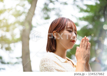 木漏れ日の中で祈る女性 134527862