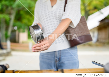 神社で柄杓を使って手を清める女性 神社で柄杓を使って手を清める女性 134527867